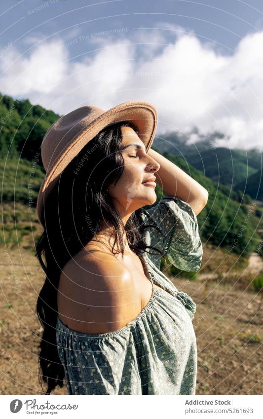 Young woman standing in mountains enjoying nature traveler sunlight journey landscape vacation tourism freedom young harmony straw hat carefree lifestyle