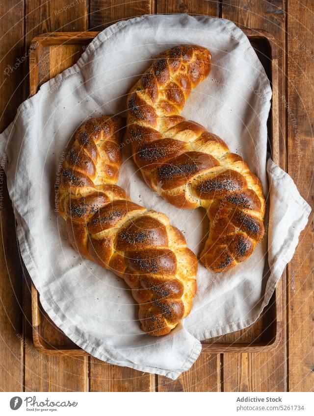 Delicious sweet bread braids on towel loaf tray serve poppy seed rustic golden meal napkin tasty challah bakery fresh delicious gourmet bun baked wooden crust