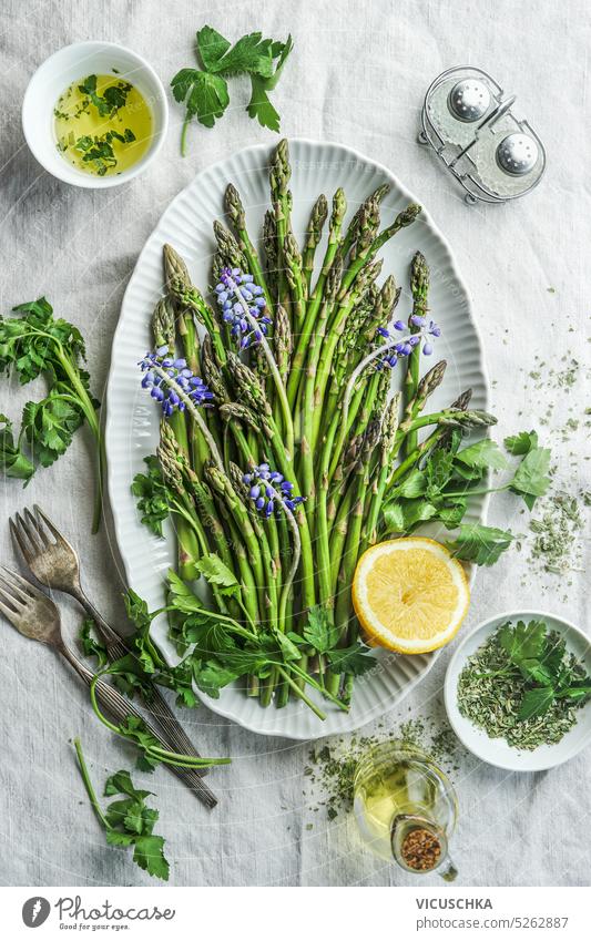 Green asparagus in plate with cooking ingredients, top view green asparagus above table vegetarian parsley vegetable raw vegan food healthy fresh