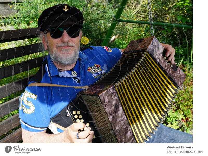 Elderly man with a captain's hat sits outside and plays a diatonic button accordion Face Person Musical Instrument vintage old outdoors male horizontal antique