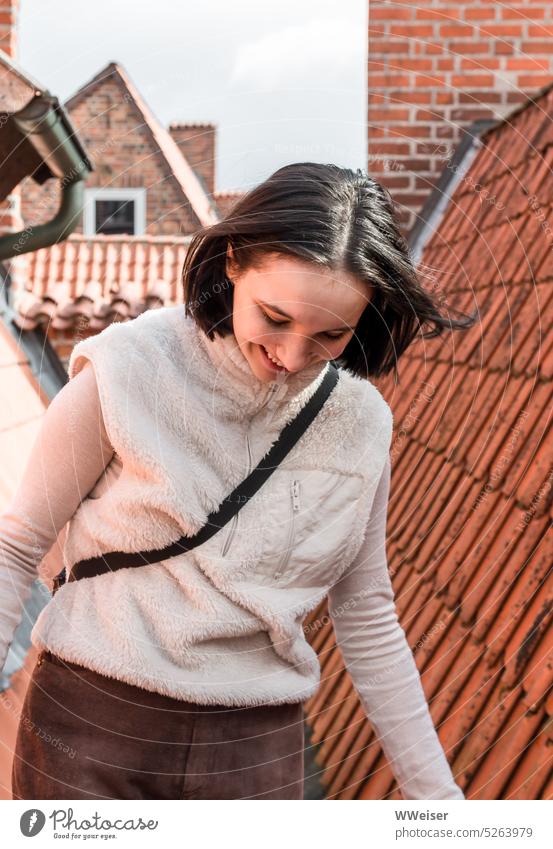 A young woman walks across the roofs of the old city Girl Woman Smiling fortunate adventurous courageous balance brick Pointed roof Hanseatic City Small Town