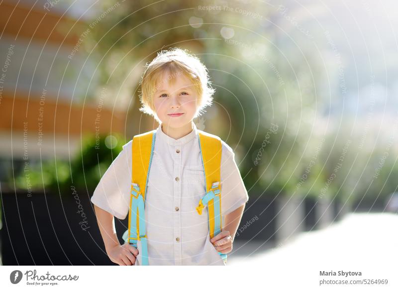 Little schoolboy joyfully goes to school after holiday. Child in a yard of schoolhouse. Quality education for children. Kids back to school kids portrait