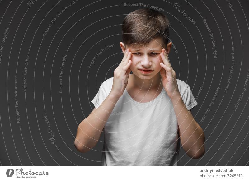 Handsome teenager boy wearing casual white t-shirt standing over isolated background suffering from headache desperate and stressed because pain and migraine. Hands on head.