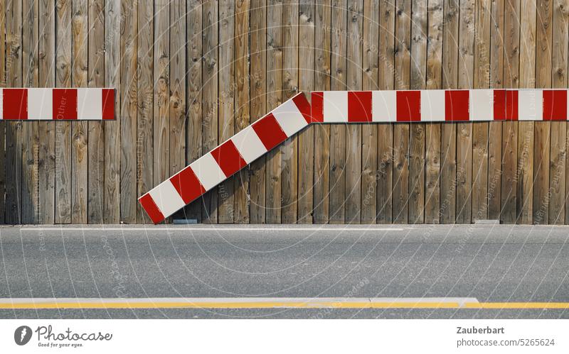 Red and white mark on construction fence, interrupted, road in front of it, abstraction and symbolic for interruption, gap, break Reddish white intermittent