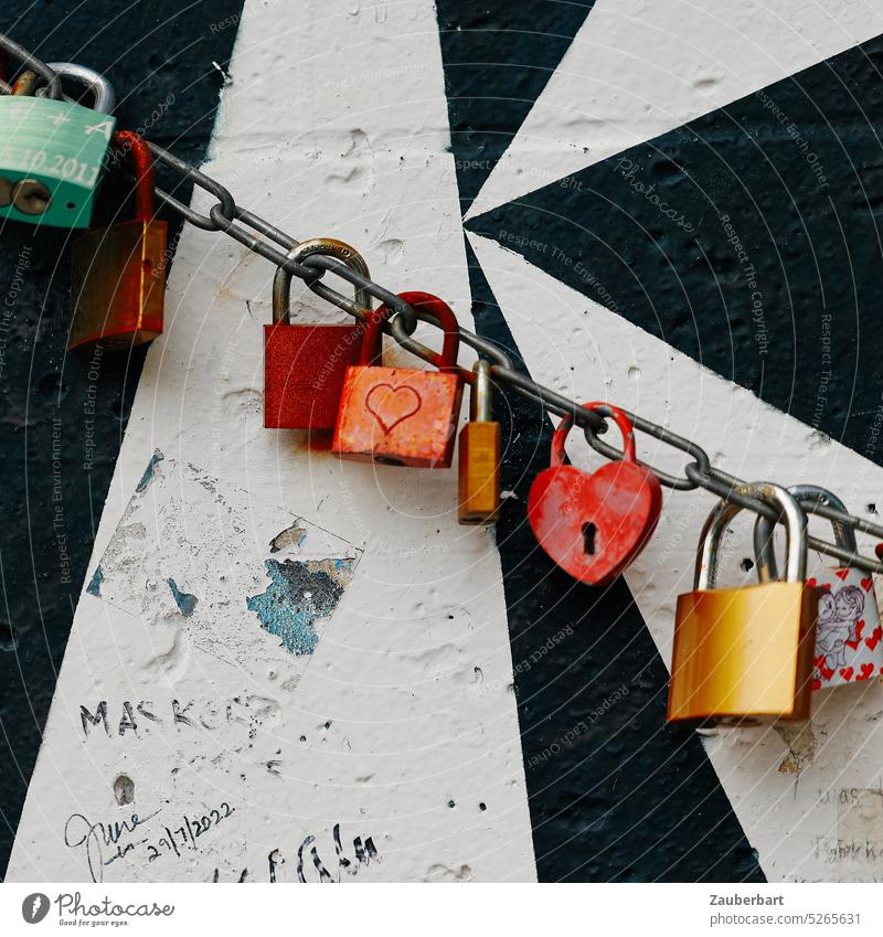 Locks in red on chain, lined up in front of black and white pattern on segment of Berlin Wall Red Love vowed to love Chain Row group background Wall (barrier)
