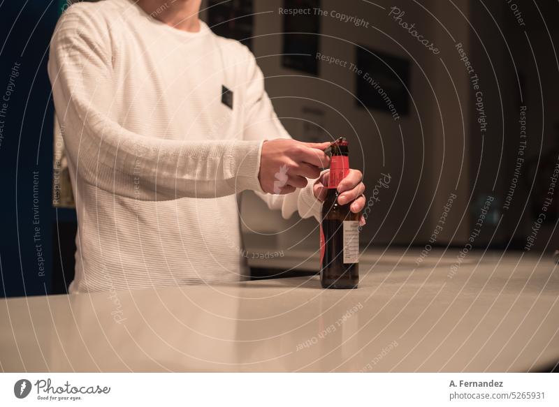 Detail of a bartender opening a bottle of beer using a bottle opener at a bar counter. waiter beer bottle Bottle Bottle opener Bottle of beer barman hand detail