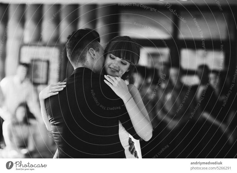 Young beautiful couple of brides dancing in a restaurant celebrating a wedding. wedding day. black and white photo, a woman in a wedding dress, a man in a suit.