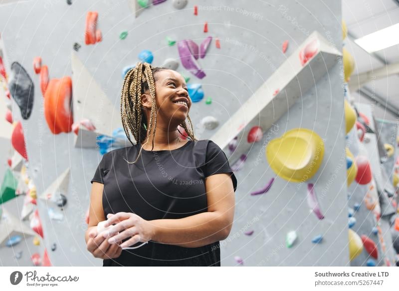 Smiling Woman Rubbing Hands With Chalk Ready For Climbing Wall At Indoor Centre woman climber bouldering climbing center centre indoors wall rubbing hands chalk