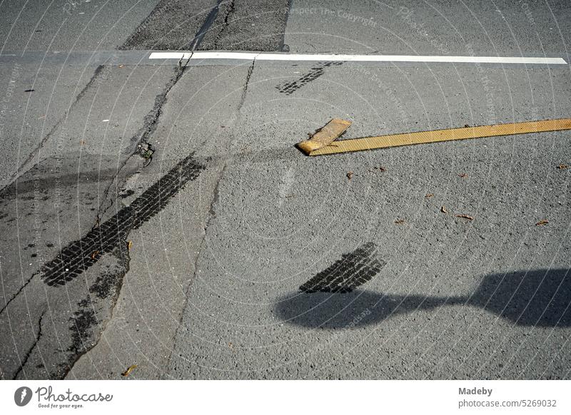 Detached yellow road marking foil on gray asphalt in sunshine at a construction site in the city center of Wuppertal in the Bergisches Land region of Germany