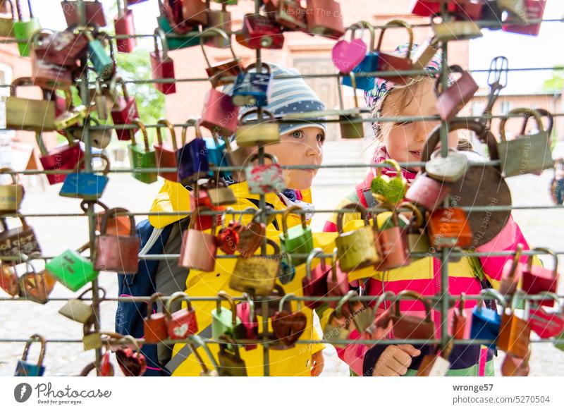 Two girls admire a collection of love locks topic day Collection Love Locks Girl Marvel at look at Display of affection Declaration of love Public Infatuation