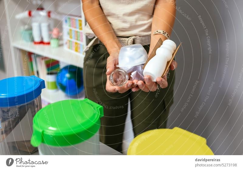 Female teacher holding waste to recycle with selective trash bins in foreground unrecognizable faceless female showing garbage hand can ecology classroom