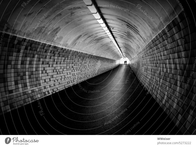 Two people reach the end of a long tunnel hand in hand Tunnel Underpass Pedestrian Perspective Vanishing point End Light Couple at the same time in common