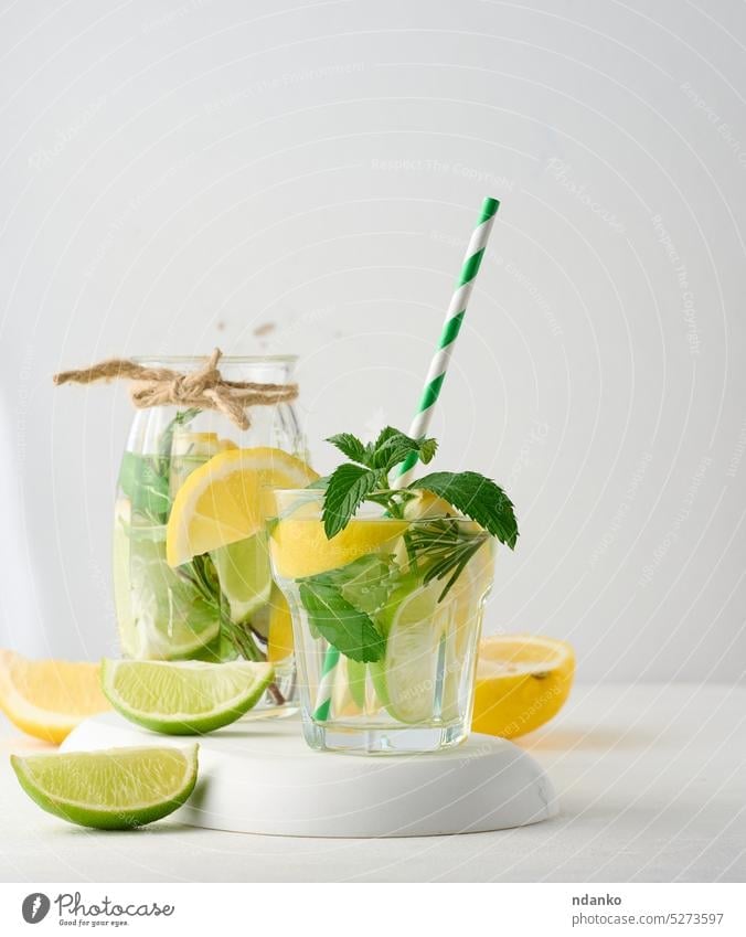 Lemonade in a transparent glass with lemon, lime, rosemary sprigs and mint leaves on a white background lemonade drink cocktail refreshment fruit ice green