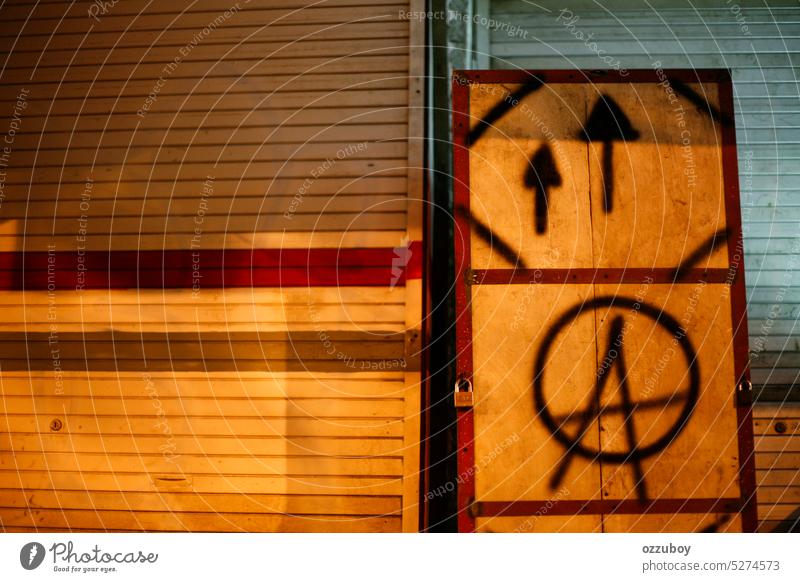 symbol of anarchy A letter with direction painting with black spray paint on a board of a shop vandalism sign graffiti grunge punk anarchist rough urban texture
