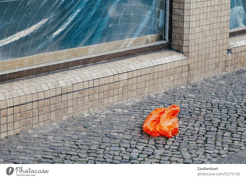 Red plastic bag on sidewalk in front of large window pane, covered with plastic film Paper bag Plastic bag Orange Trash waste off Environment