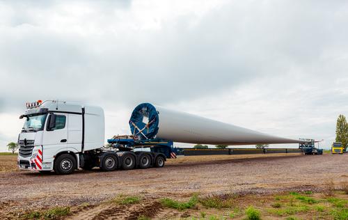 Truck in the field. Rotor blade for wind turbine. Special transport of a blade for a wind turbine on a special semi-trailer. lorry Field Wind energy plant