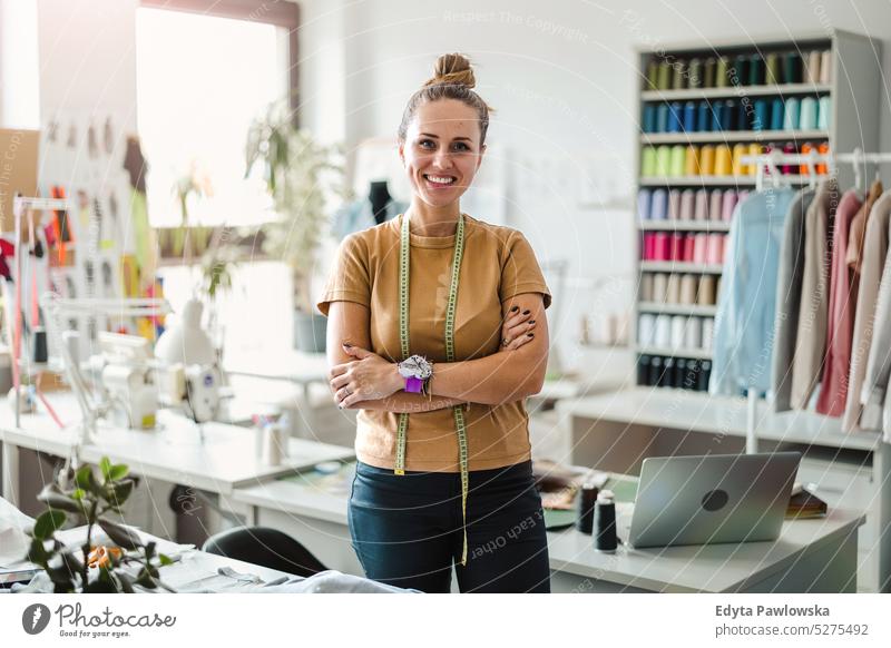 Portrait of young female fashion designer standing at her workplace craft tailoring manufacturing handmade seamstress small business sewing machine workshop
