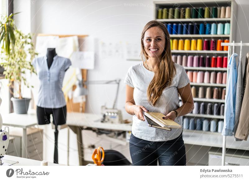 Portrait of young female fashion designer standing at her workplace craft tailoring manufacturing handmade seamstress small business sewing machine workshop