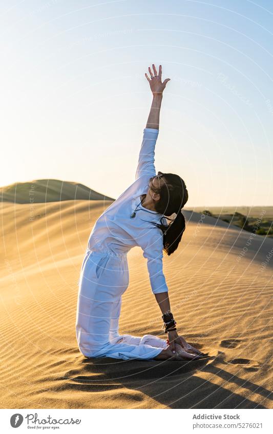 Fit lady performing yoga pose in sandy terrain woman stress relief mindfulness desert wellbeing balance kneel vitality female harmony position zen cloudless