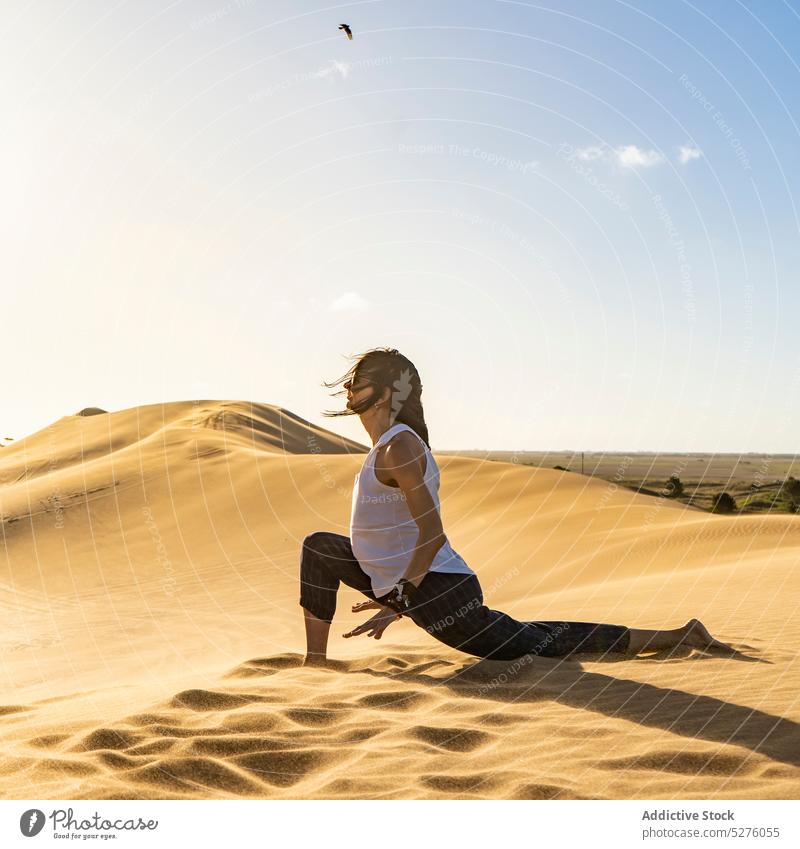 Young woman meditating in Crescent Lunge pose in desert practice yoga crescent lunge anjaneyasana exercise wellness harmony healthy spirit la frontera pinamar
