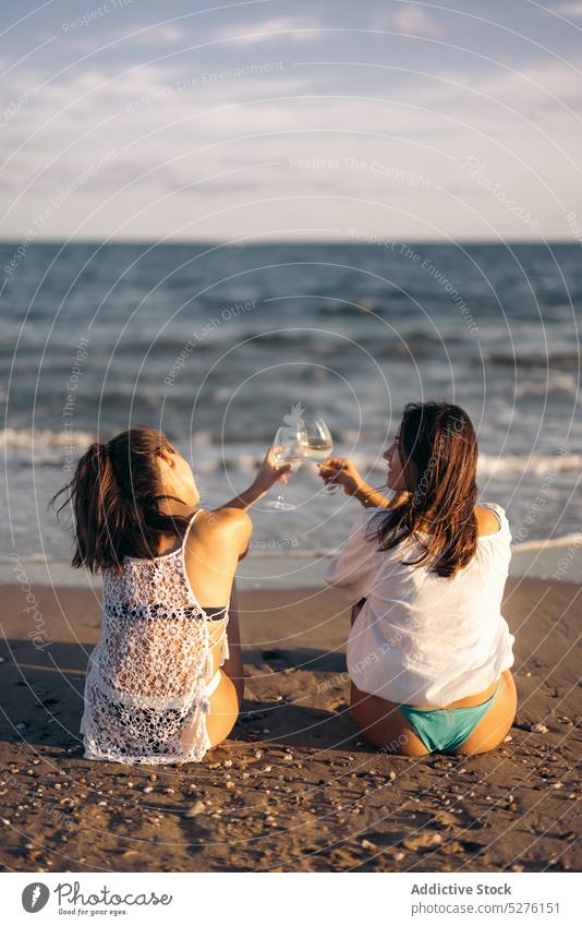 Girlfriends clinking glasses near sea women couple beach wine toast romantic evening lesbian female young wineglass together love lgbt resort cheers affection