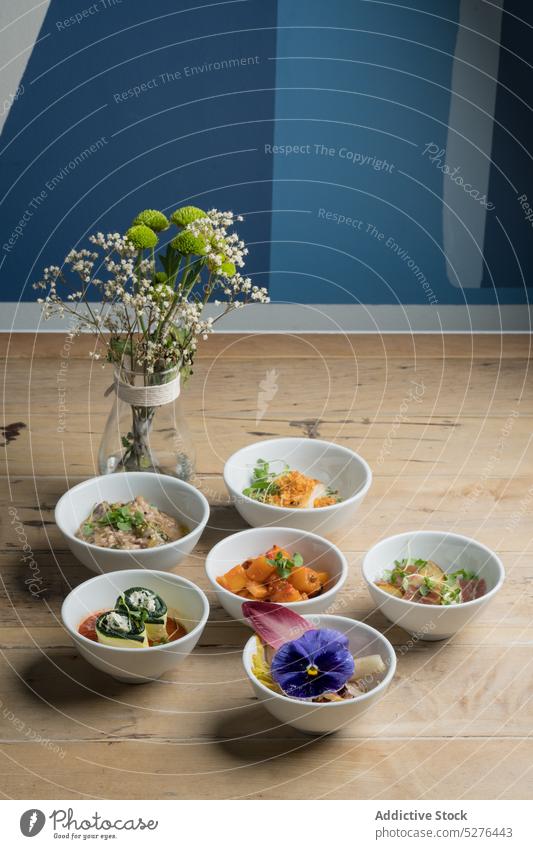 Various dishes near glass vase with flowers food portion bowl bouquet bloom blossom delicious fresh table floor tasty assorted natural various ceramic yummy