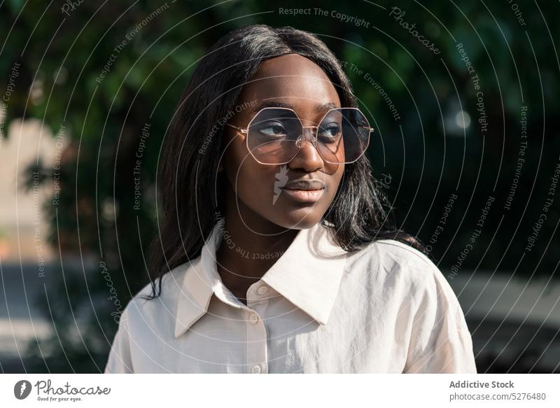 Smiling black woman in big eyeglasses positive smile appearance sunglasses portrait park style personality summer nature confident female young long hair