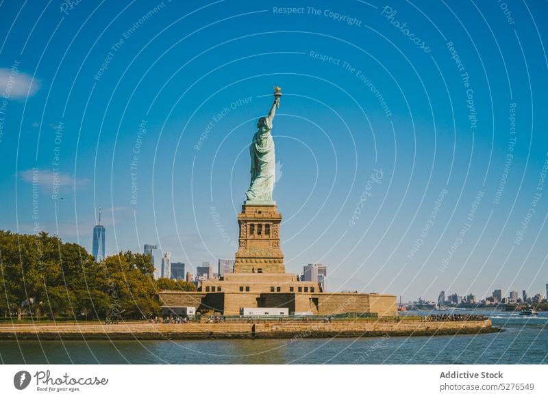 Famous monument on seafront in sunlight statue of liberty embankment cityscape famous water blue sky cloudless landmark river new york liberty island usa