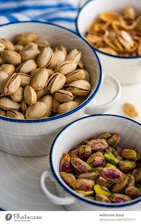 Ceramic bowls full of organic nuts concept concrete cooking dark diet food green healthy keto ketogenic nutshell pistachio plant based raw rustic stripe table