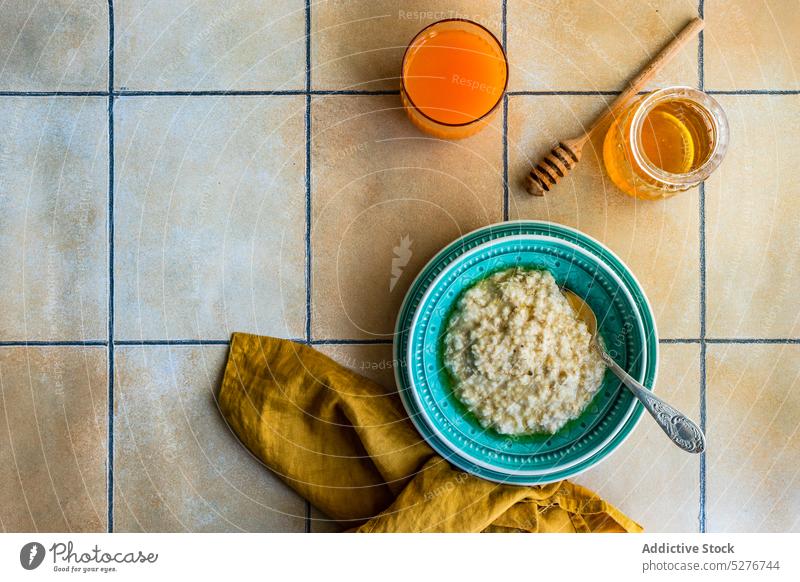 Healthy breakfast with oatmeal porridge bowl food healthy honey juice morning napkin ceramic spoon table tile plate fresh delicious nutrition sweet cereal