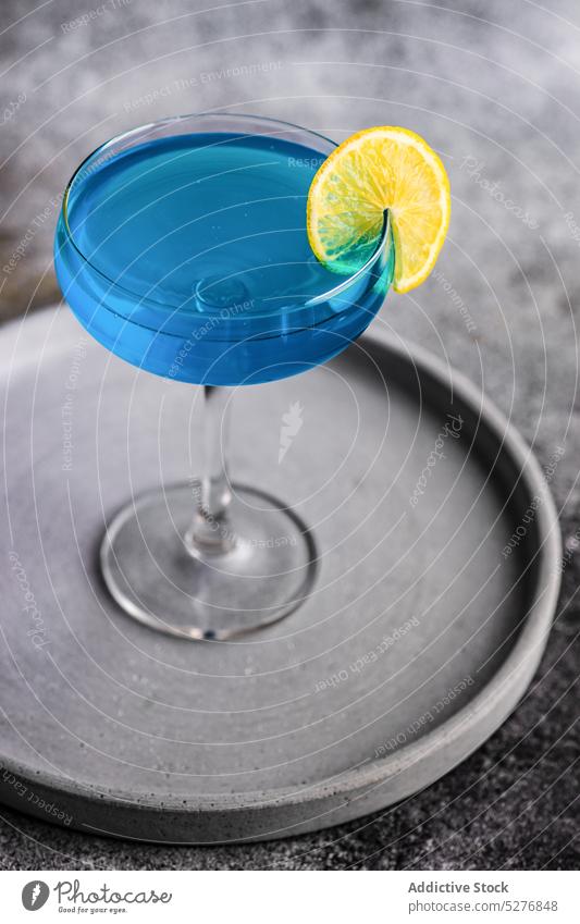 Glass of blue kamikaze drink alcohol alcoholic background beverage cocktail concrete crystal funny glass gourmet ice lemon light liqueur party shot still life