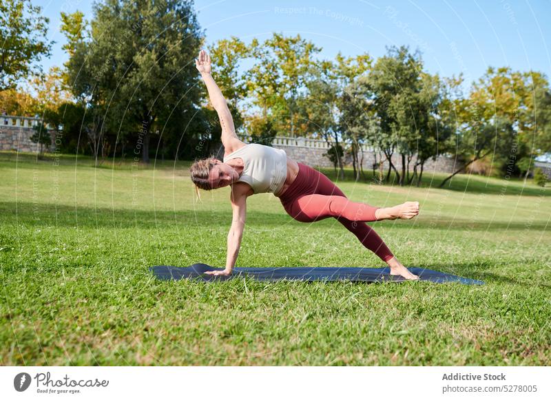 Slim woman practicing yoga doing side plank kick asana practice workout mat flexible motivation training park exercise female slim healthy wellness sportswear