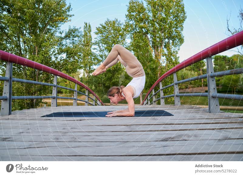 Athletic female doing yoga in scorpion pose on bridge woman asana vrischikasana a exercise balance athlete motivation park sunlight wellness sporty