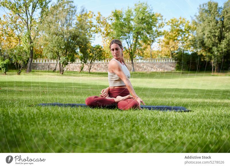 Concentrated woman doing yoga in seated twist pose asana legs crossed parivritta sukhasana meditate spirit stress relief healthy lifestyle female wellness