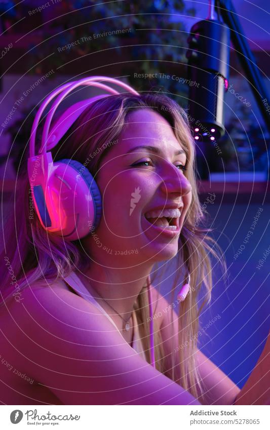 Cheerful young woman in headphones laugh cheerful portrait headset device neon gadget pink light dark smile illuminate blond female millennial happy wireless