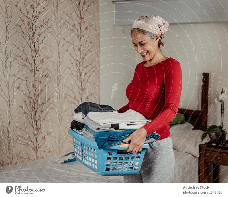 Cheerful woman carrying basket with clothes housewife laundry smile chore routine happy housework positive household home female cheerful hygiene clean