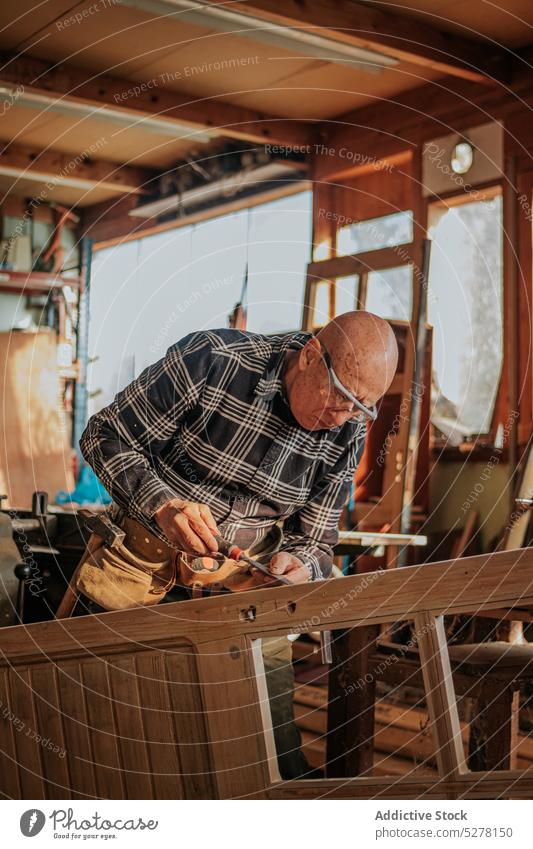 Senior carpenter using chisel in workshop man woodworker cut craftsman plank skill artisan carpentry male tool instrument equipment process manual elderly