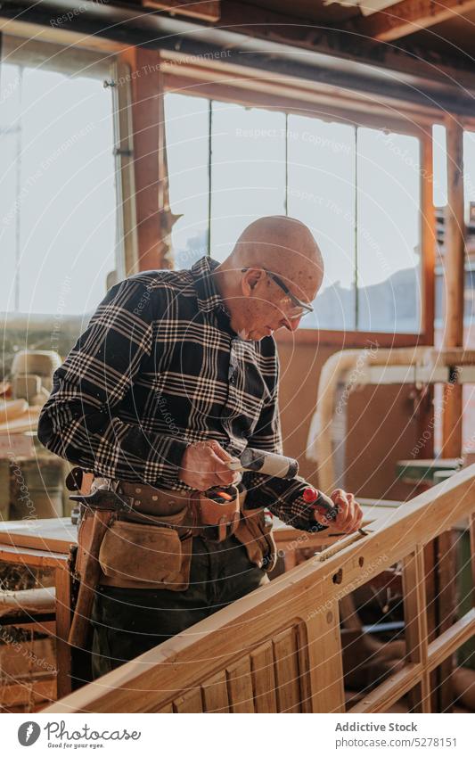 Senior carpenter using chisel and hammer in workshop man woodworker cut craftsman plank skill artisan carpentry male tool instrument equipment manual elderly