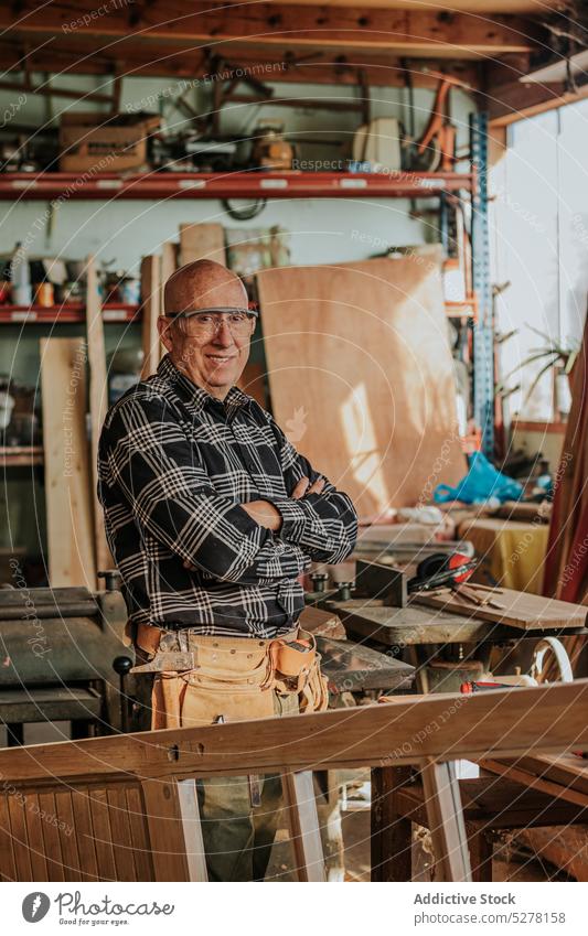 Senior craftsman looking at camera in workshop carpenter smile happy joinery professional cheerful job artisan male woodwork lumber senior aged positive timber