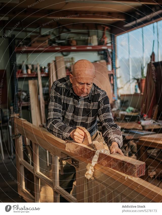 Senior carpenter using jointer in workshop man woodworker cut workbench planner process joinery male plank craftsman professional tool job wooden manual artisan
