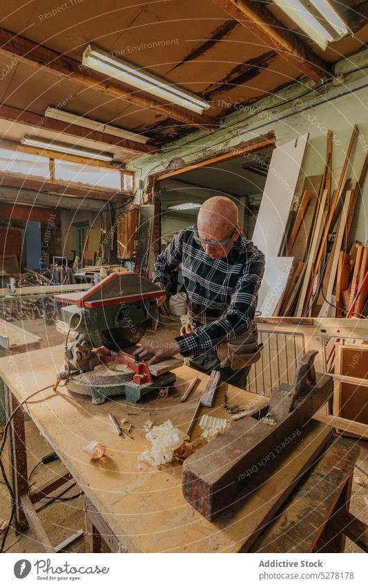 Carpenter cutting wood on circular saw table man carpenter joinery workshop board plank workbench lumber woodworker craftsman artisan male wooden job timber