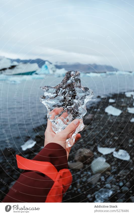 Crop woman showing transparent ice traveler shore sea cold winter outerwear iceland female piece weather frozen coast water demonstrate nature climate clean