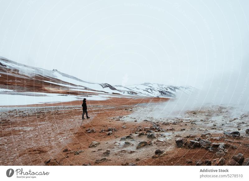 Traveler walking in geothermal valley traveler steam hill gray sky snow winter iceland hverir nature landscape volcanic terrain climate frost north scenery