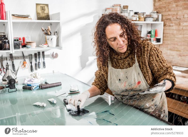 Female artisan examining metal plate craftswoman examine photoengraving studio sponge ink prepare creative industry female mature middle age manual hobby dip