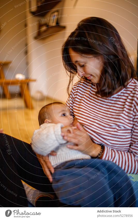Mother breastfeeding baby on floor mother calm motherhood child cute parent childcare together love adorable kid living room home drink nutrition milk eat mom
