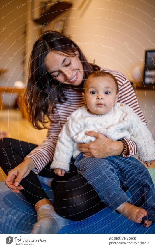 Cheerful woman hugging cute boy on floor at home mother son together child love positive smile embrace happy parent childhood bonding adorable casual mom