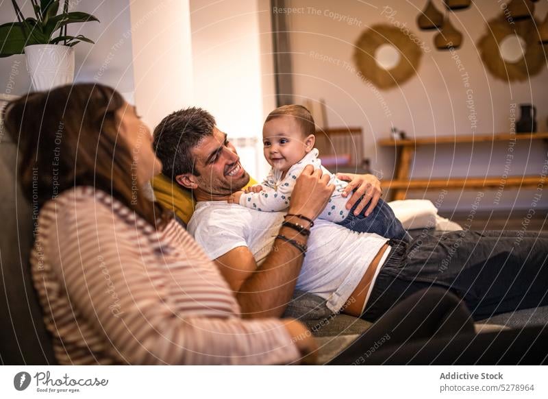 Happy family spending time together on couch play home mother parent toddler love child son weekend embrace father hug kid living room bonding little sofa