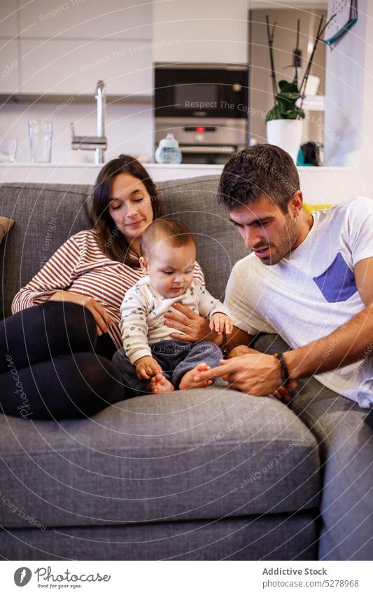 Happy parents with baby on sofa family play positive together relationship home spend time love child mother happy kid living room childhood father bonding son