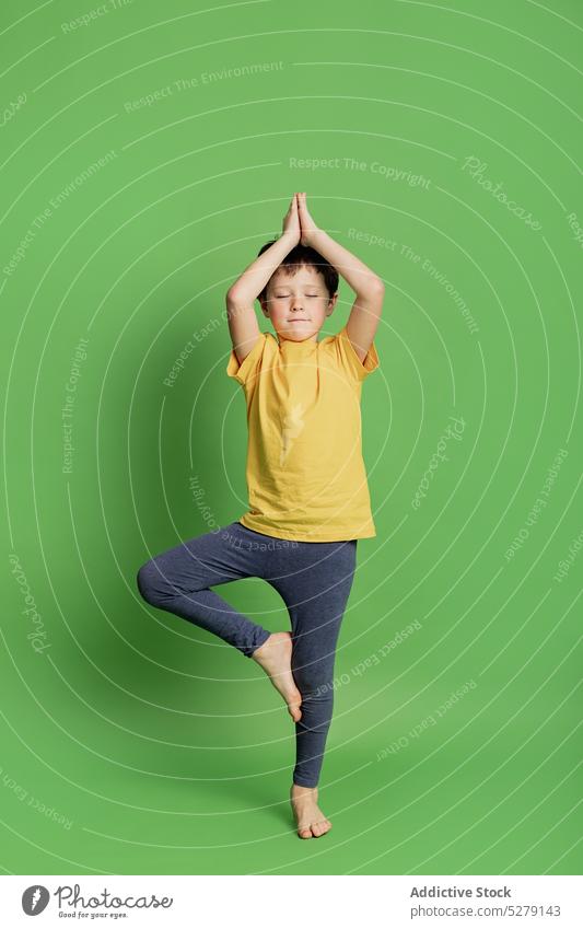 Calm boy practicing tree pose child kid calm yoga asana practice sportswear balance wellness barefoot studio healthy childhood concentrate eyes closed
