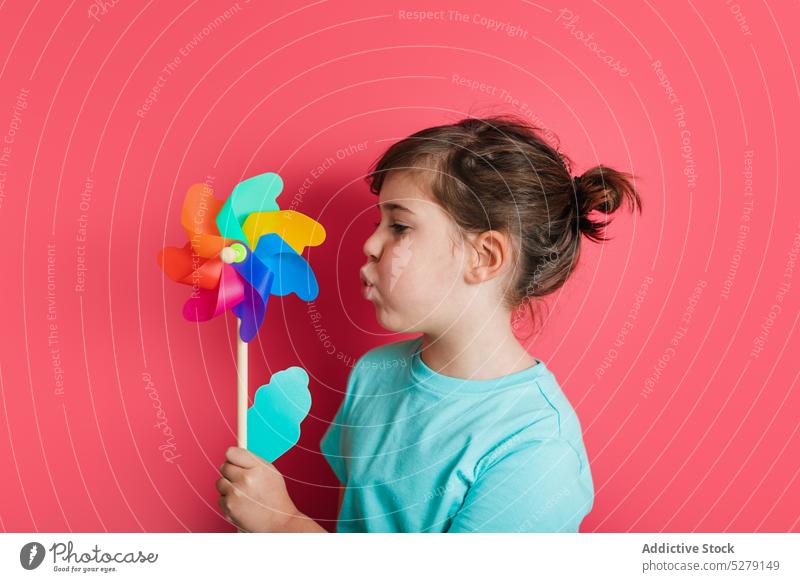 Funny kid blowing on pinwheel girl rainbow play leisure entertain interest game funny playful cheerful toy child individuality childhood sweet expressive